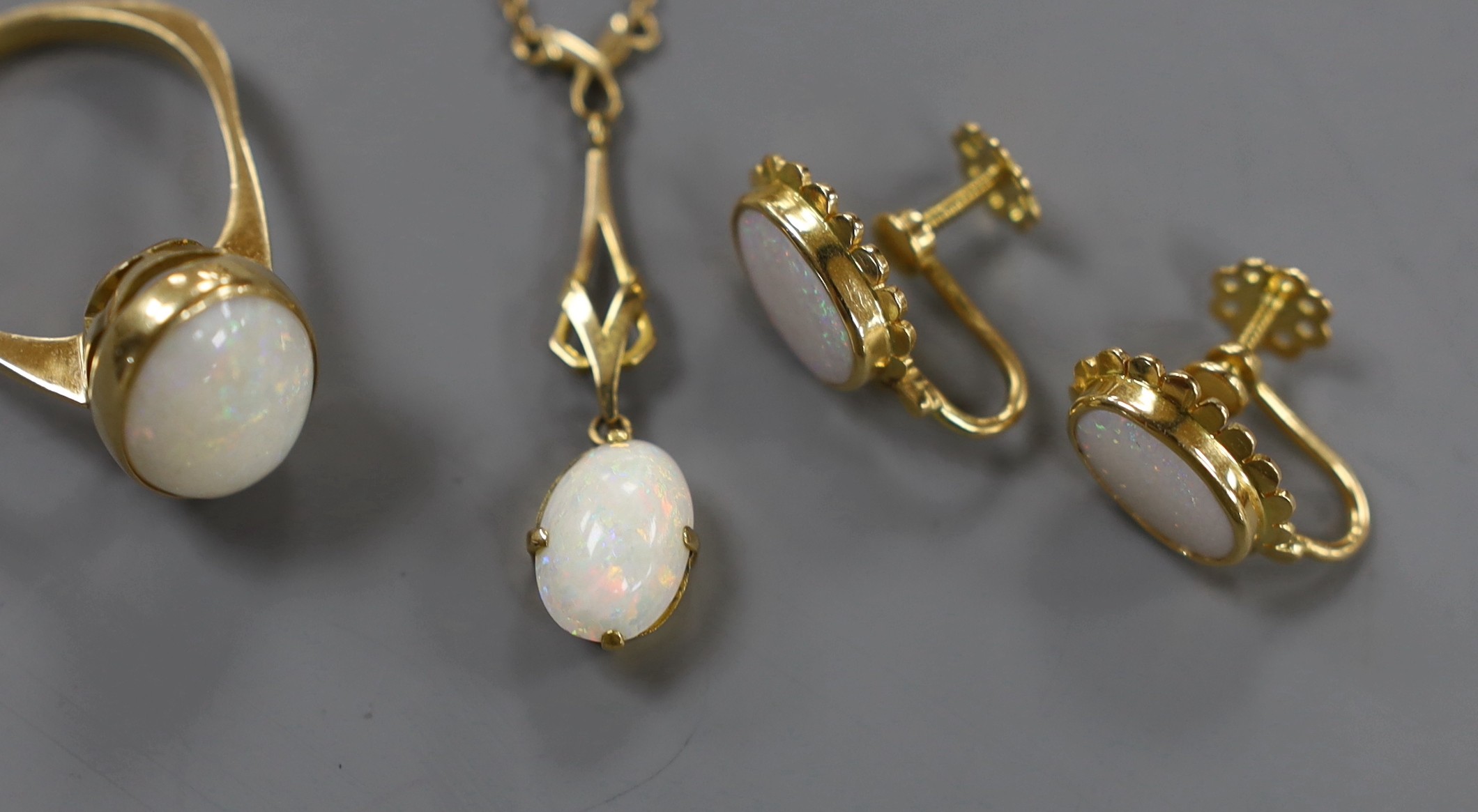 A 750 yellow metal and oval cabochon white opal set ring, size U/V, gross weight 6.2 grams, together with a pair of yellow metal and opal set ear clips and a similar pendant necklace.